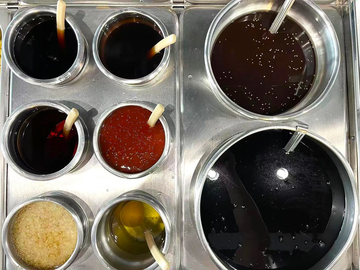 Assorted sauces and oils for custom stir-fry bowls at Otasty Mongolian BBQ Restaurant in Citrus Heights